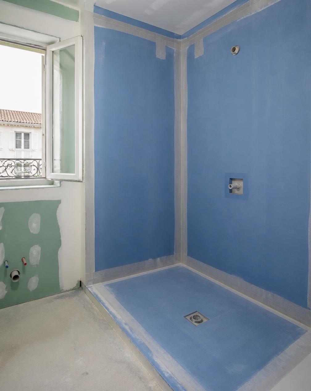 Membrane d'étanchéité bleue et bandes de renfort appliquées dans les angles de la douche